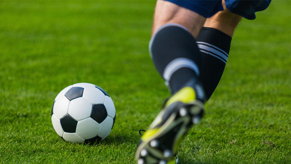 Recreational footballer returning to training on grass pitch after knee injury rehabilitation