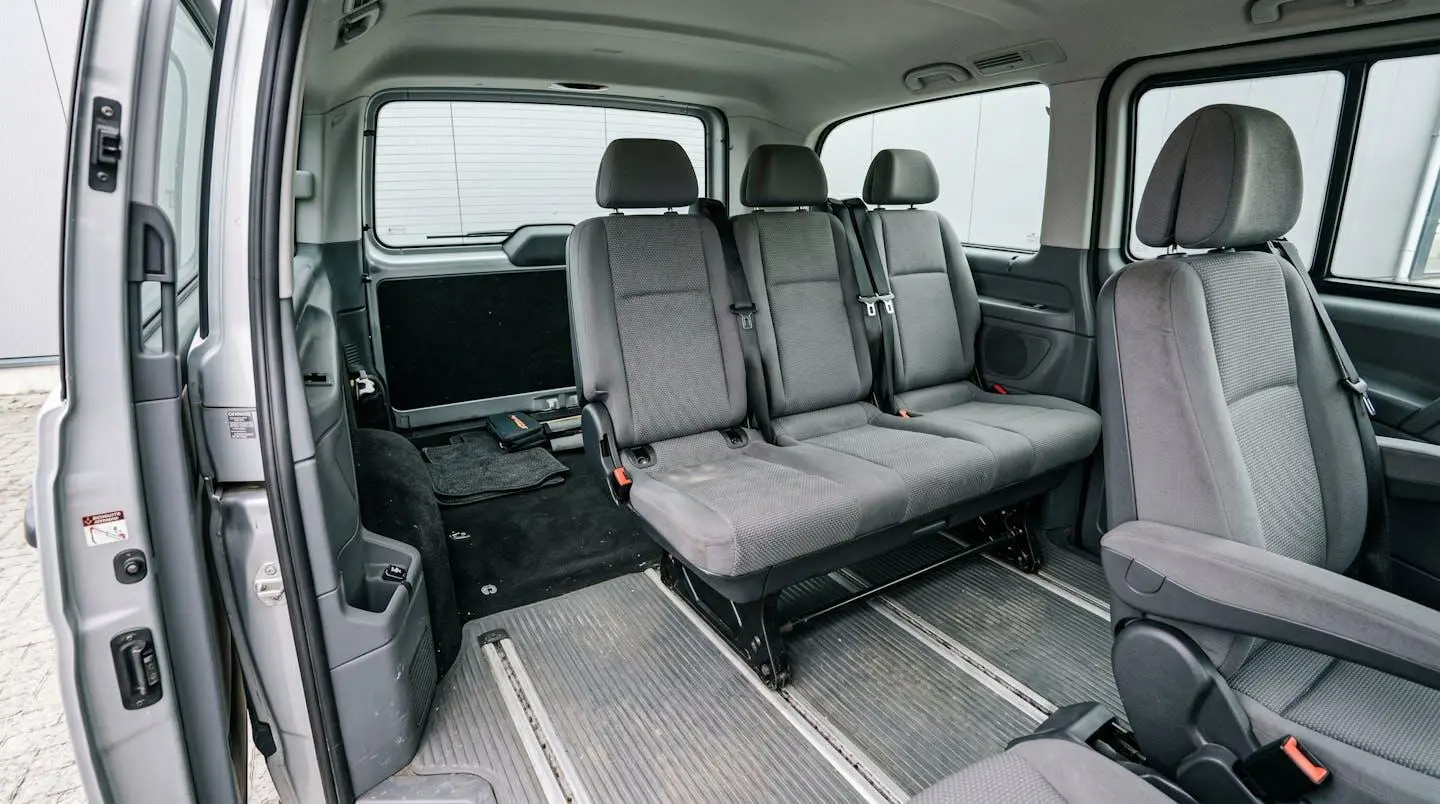 Minibus interior showing third-row seats in upright position with limited boot space visible behind, demonstrating capacity trade-off between passenger seats and luggage area